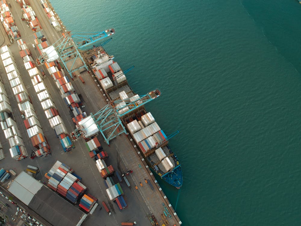 Top view of harbor with containers and cargo ships located near calm rippling sea water 