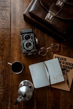 A vintage Rollei camera with coffee, glasses, and open notebook on a wooden surface, ideal for retro themes.