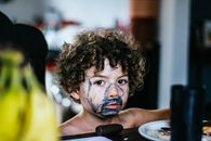 Boy with painted face standing near table