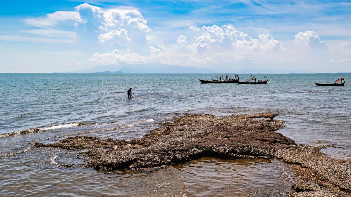 Fishing boats moored along a rocky shoreline in Kep