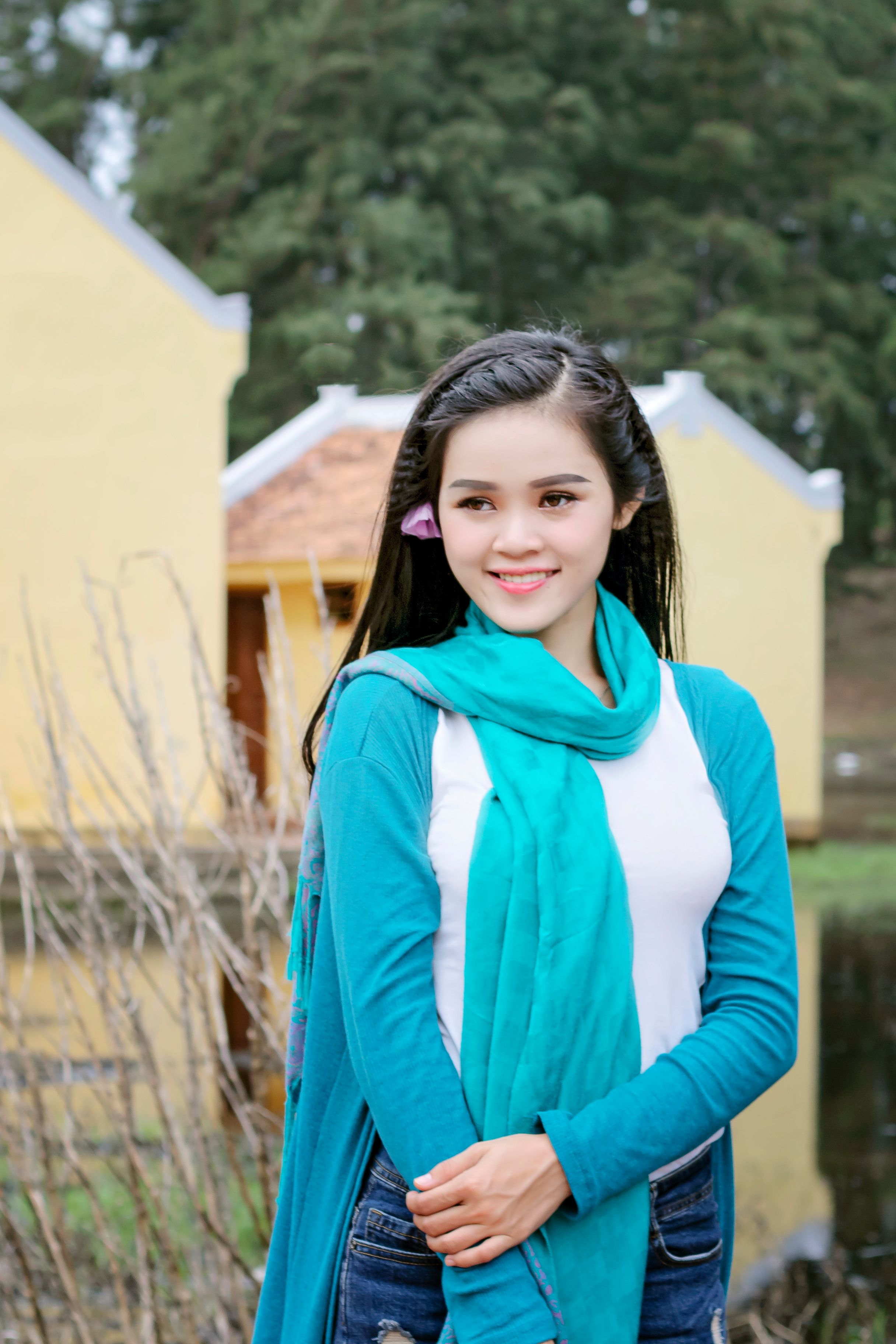 Asian woman in blue scarf smiling outdoors in Trà Vinh, Vietnam.
