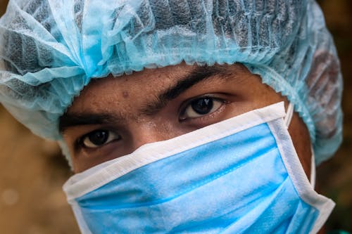 Crop ethnic male doctor in protective mask and hat