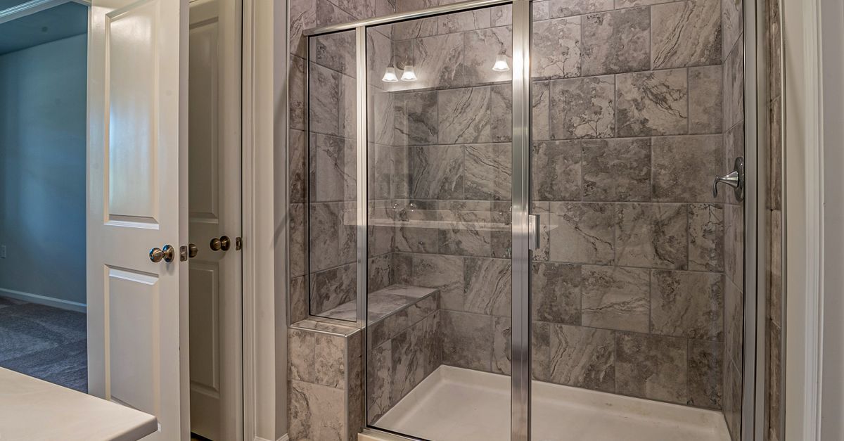 Luxurious modern bathroom with marble tiled shower and sleek glass doors.