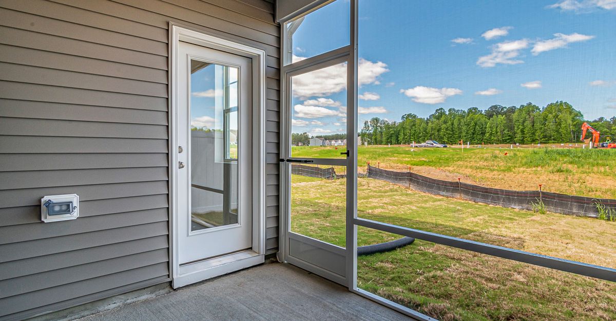 Enjoy a bright, scenic view from a modern patio with glass door and lush backyard.
