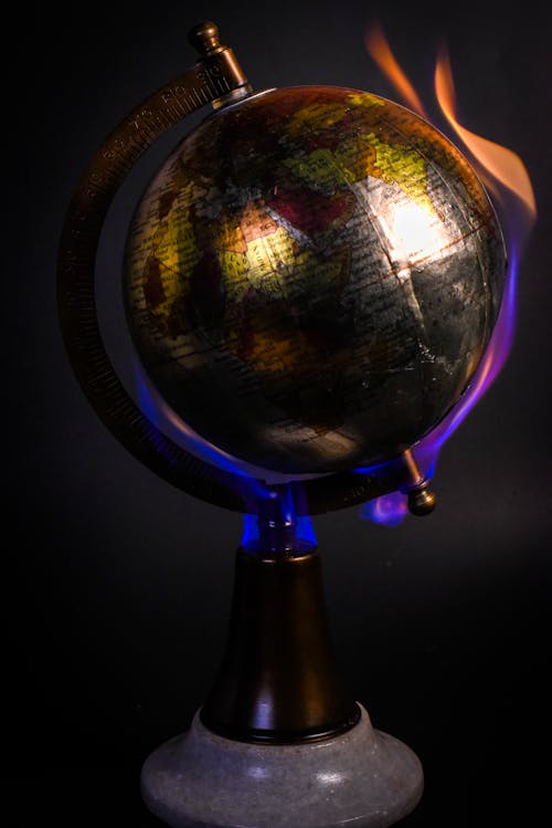 Earth globe map burning on bright fire against black wall in studio