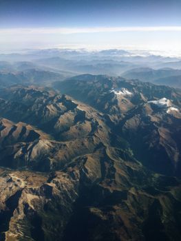 Breathtaking aerial perspective showcasing vast mountain ranges under a clear sky.