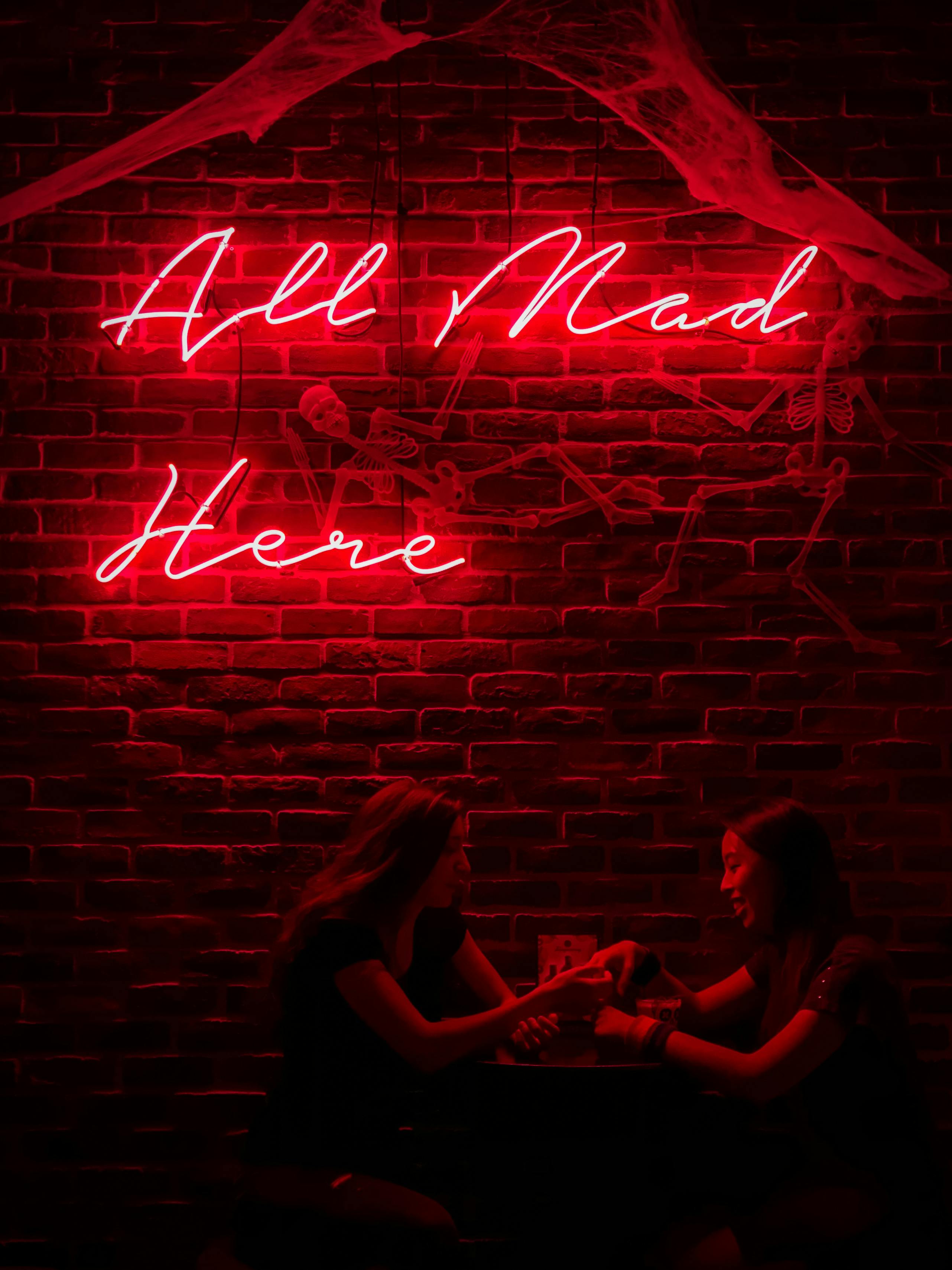 women sitting under a neon sign