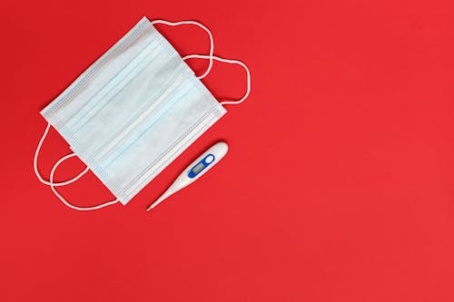 Overhead Shot of Surgical Masks Near a Digital Thermometer