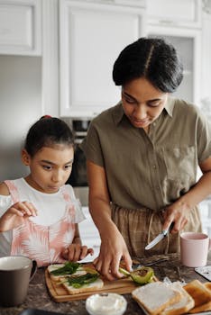 A woman and her daughter preparing a healthy avocado toast meal in a kitchen setting.