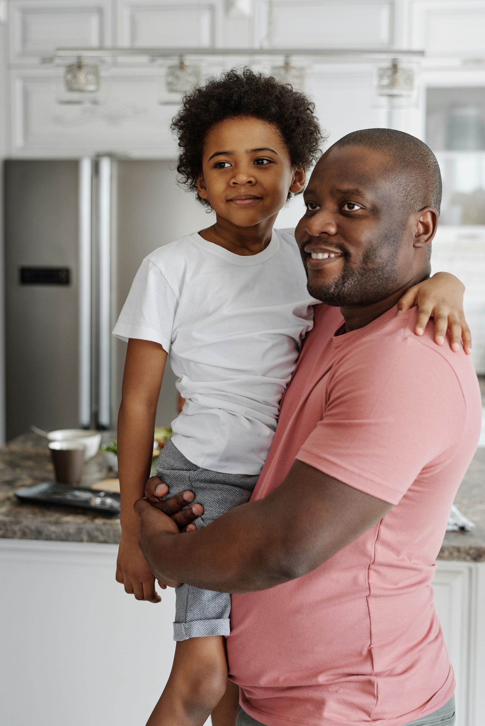 Black father holding his young son at home, warm natural light