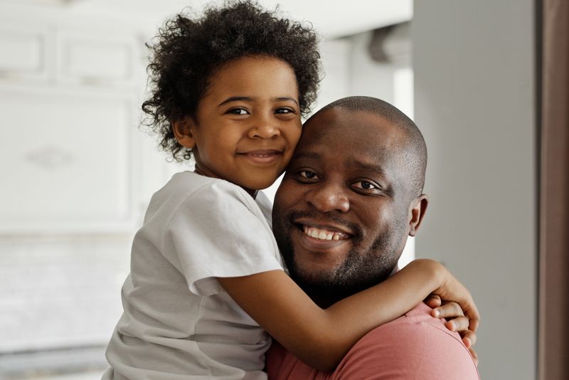 Father hugging his smiling daughter at home