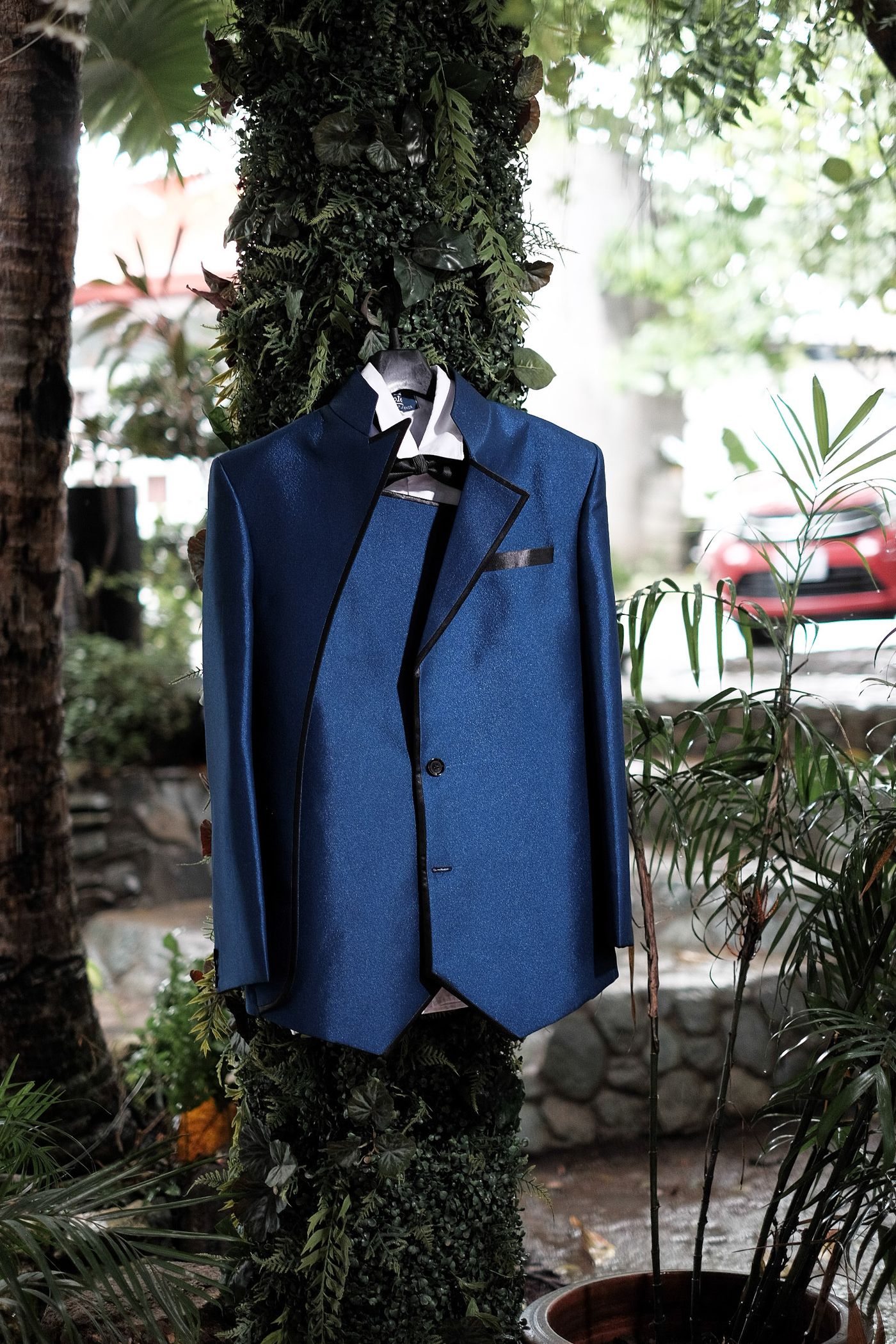 Navy suit hanging outdoors among greenery