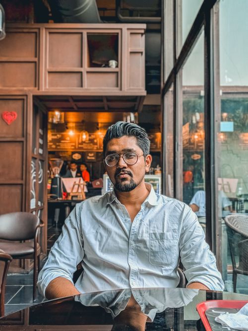 Free A man in casual attire relaxes in a cozy Ahmedabad café, enjoying the ambiance. Stock Photo