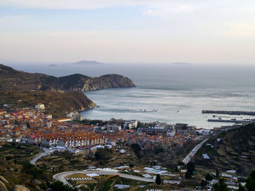 Small village with typical residential houses located on shore of endless sea near hills and  rice fields