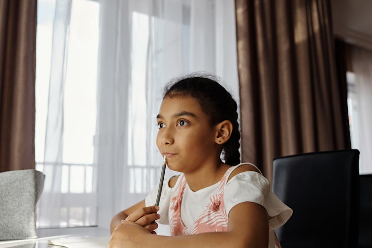 Little Girl Holding A Pencil And Thinking