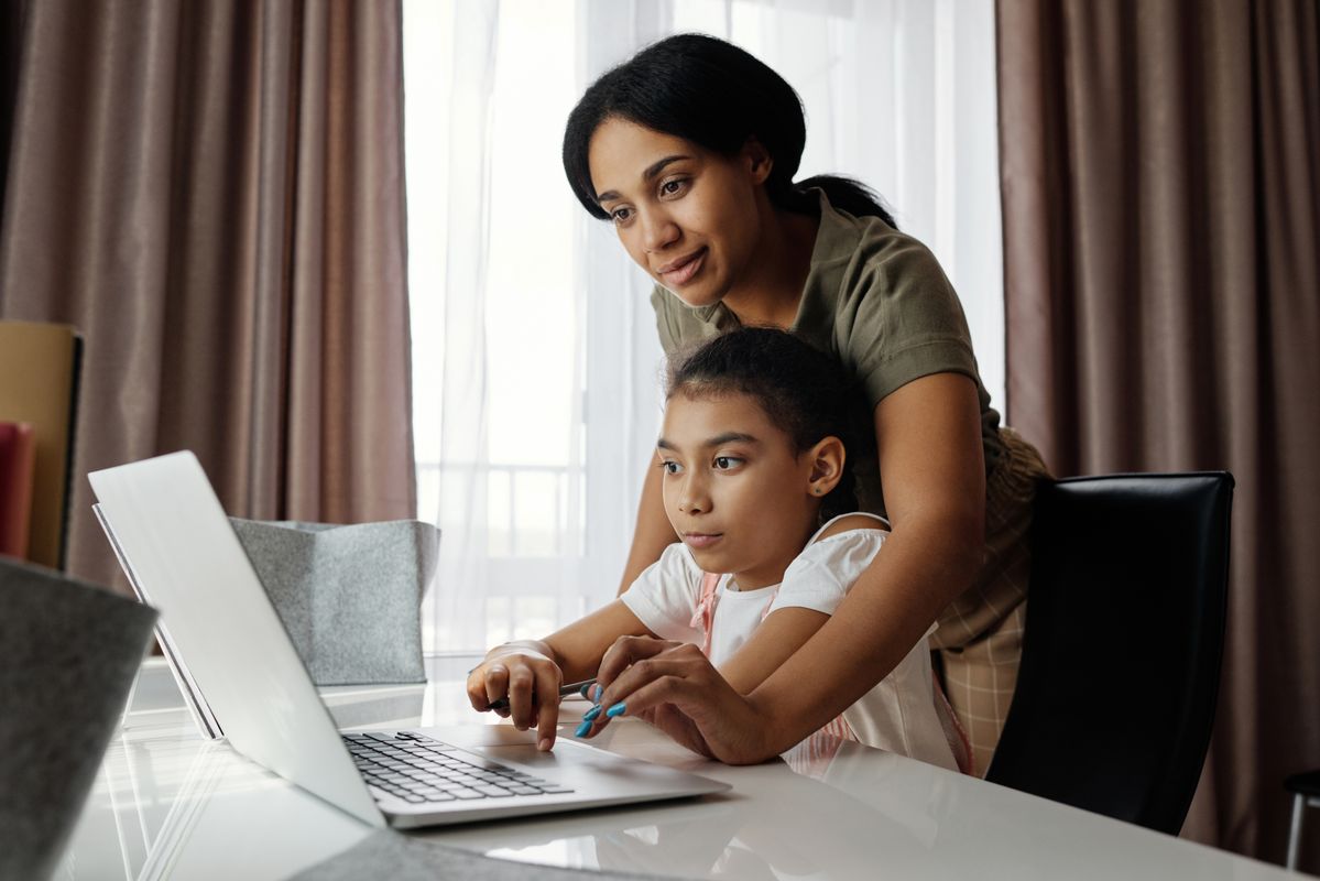 A parent helping a young scholar with an online lesson at home