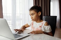 年轻女孩在家专心用笔记本电脑学习，展现了远程教育的情景