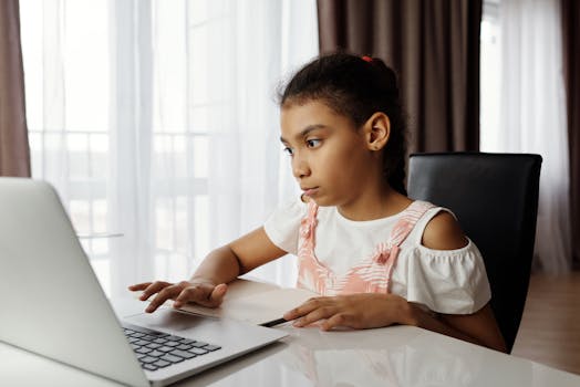 Young girl intently studying on a laptop at home, showcasing distance education.