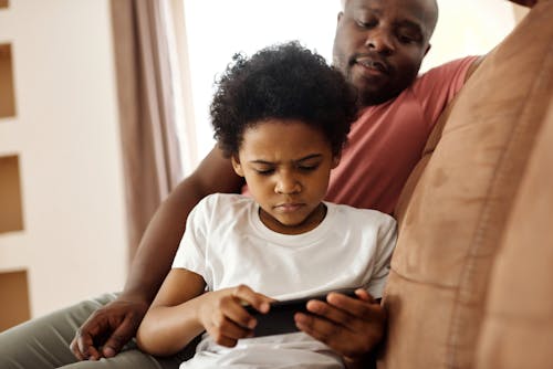 Father Looking at his Son Playing on a Smartphone
