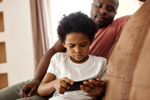 父子俩在室内专注地看着手机，享受休闲时光