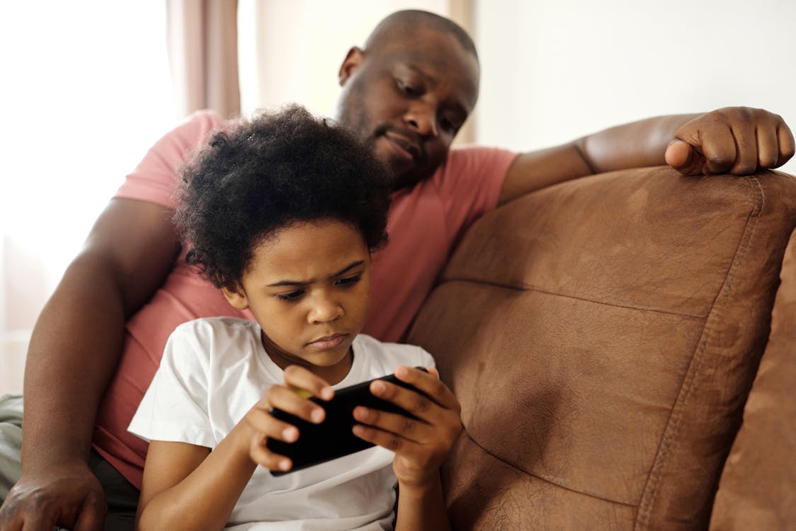 Father Watching his Son Playing on a Smartphone