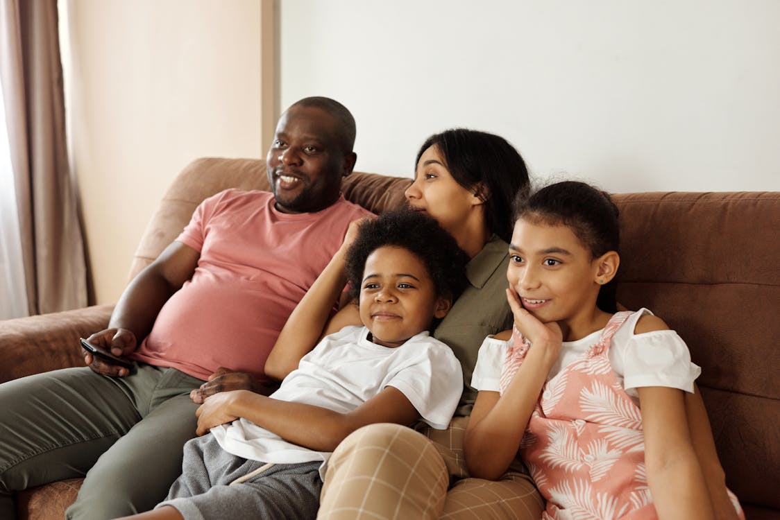 Free Happy Family Sitting on a Couch and Watching TV Stock Photo