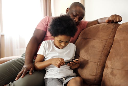 Padre Guardando Suo Figlio Che Gioca Su Uno Smartphone