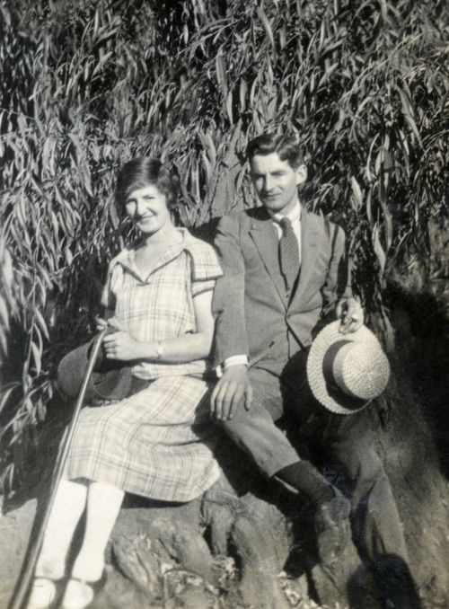 Free A black and white photo of a couple in vintage clothing sitting outdoors, exuding timeless romance. Stock Photo