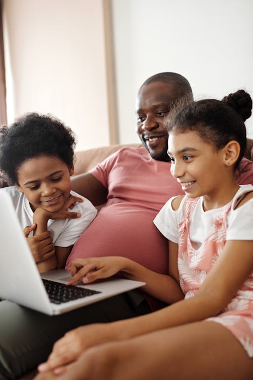 Free Happy Family Sitting and Looking at a Laptop Stock Photo