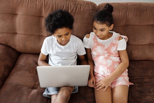 Hermanos Sentados En Un Sofá Y Mirando Una Computadora Portátil