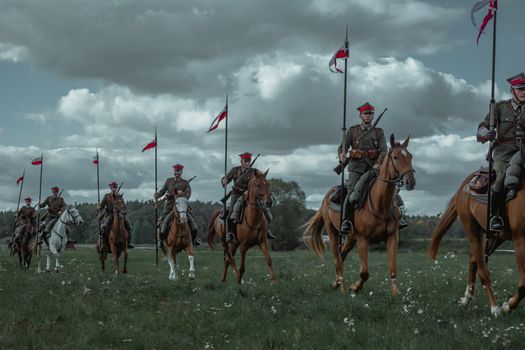 Polish soldiers on horseback holding flags, showcasing historical military cavalry.