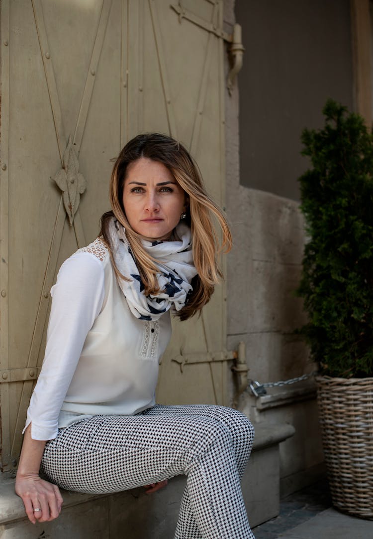 Calm Young Woman Sitting On Bench On Porch