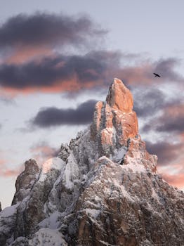 Majestic snow-covered mountain peaks under dramatic skies at sunrise in Trentino-Alto Adige.