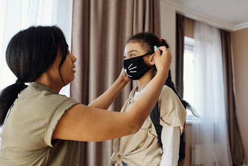 Ibu Mengenakan Masker Wajah Pada Putrinya