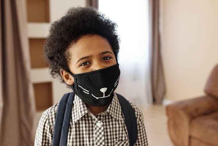 Little Boy Wearing A Face Mask With A Design