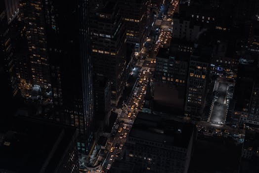 Aerial view of illuminated city streets at night, showcasing busy traffic and vibrant city life.