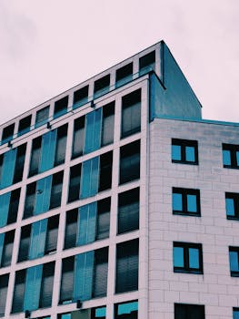 Dynamic low-angle view of a modern glass facade in urban setting. Ideal for business themes.