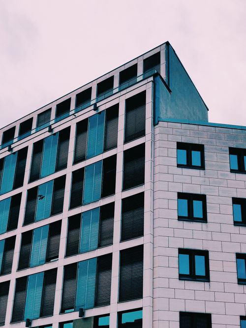 Free From below of contemporary building facade with geometric ornament and glass mirrored windows against cloudy sky Stock Photo