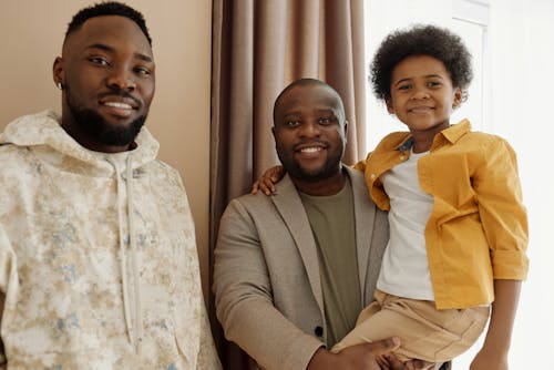 Deux Hommes Et Un Petit Garçon Souriant Et Regardant La Caméra