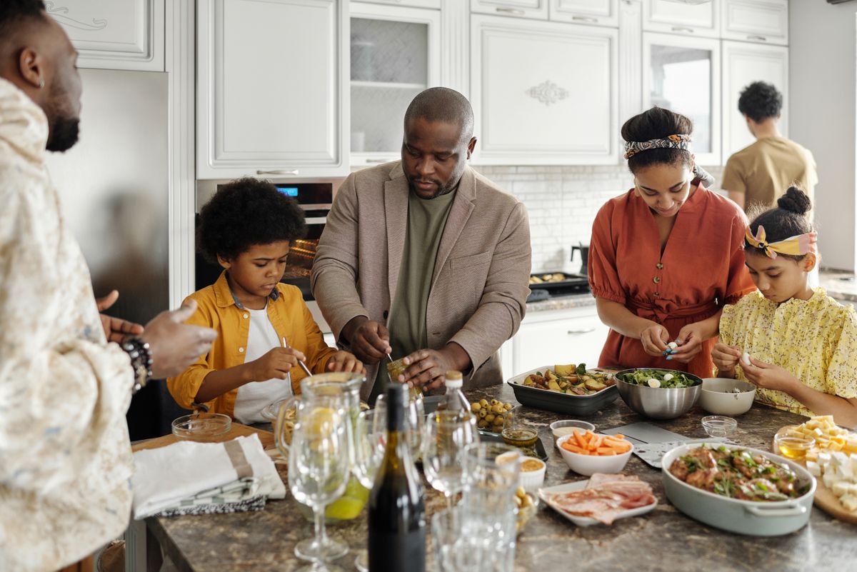 A family table set with a shared colorful home-cooked meal and hands reaching in