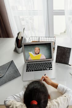 Child participating in an online class with a teacher, using a laptop at home, ideal for educational technology themes.