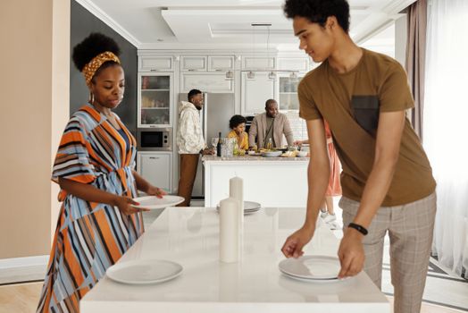 A family working together to set the dinner table in their kitchen, showcasing togetherness.