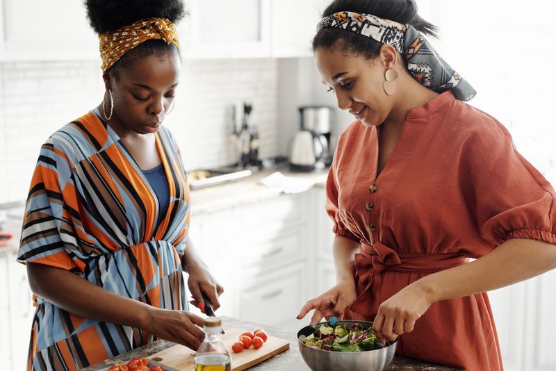 Two women preparing a healthy salad together in a kitchen
