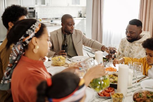 A cheerful family gathering around the dinner table enjoying food, wine, and togetherness.
