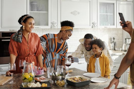 Family enjoying a cheerful gathering in a bright modern kitchen, capturing memories together.