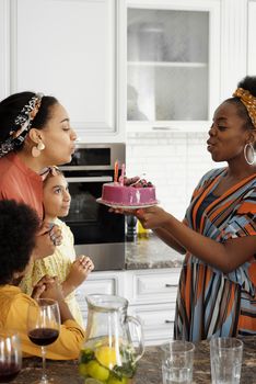 Family celebrating a birthday in the kitchen with cake and laughter.