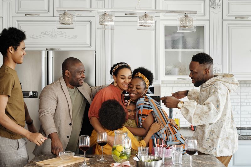 A joyful family gathering in a kitchen, embracing and smiling during a celebration.
