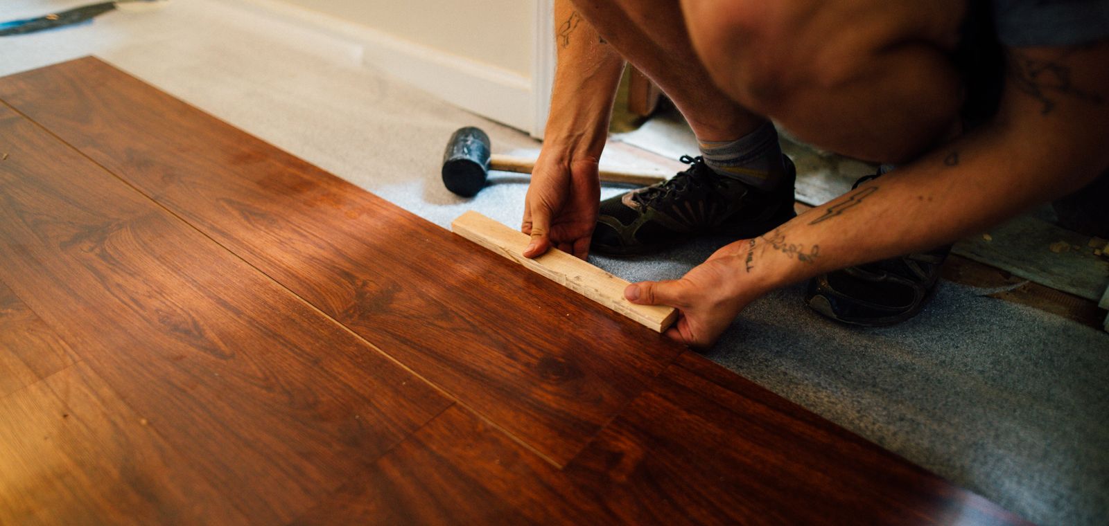Installer laying laminate wood flooring with a mallet