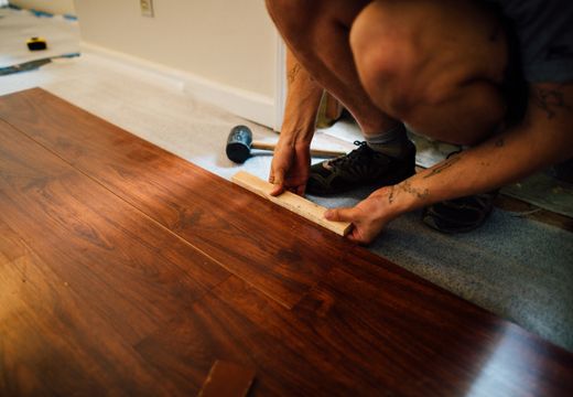 Installer laying laminate wood flooring with a mallet