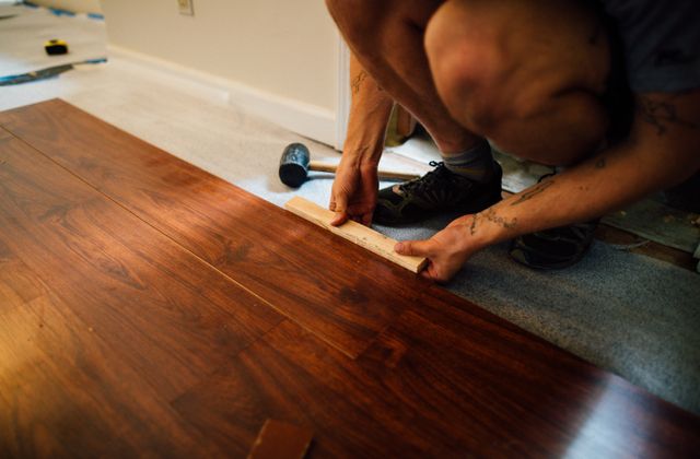Installer laying laminate wood flooring with a mallet